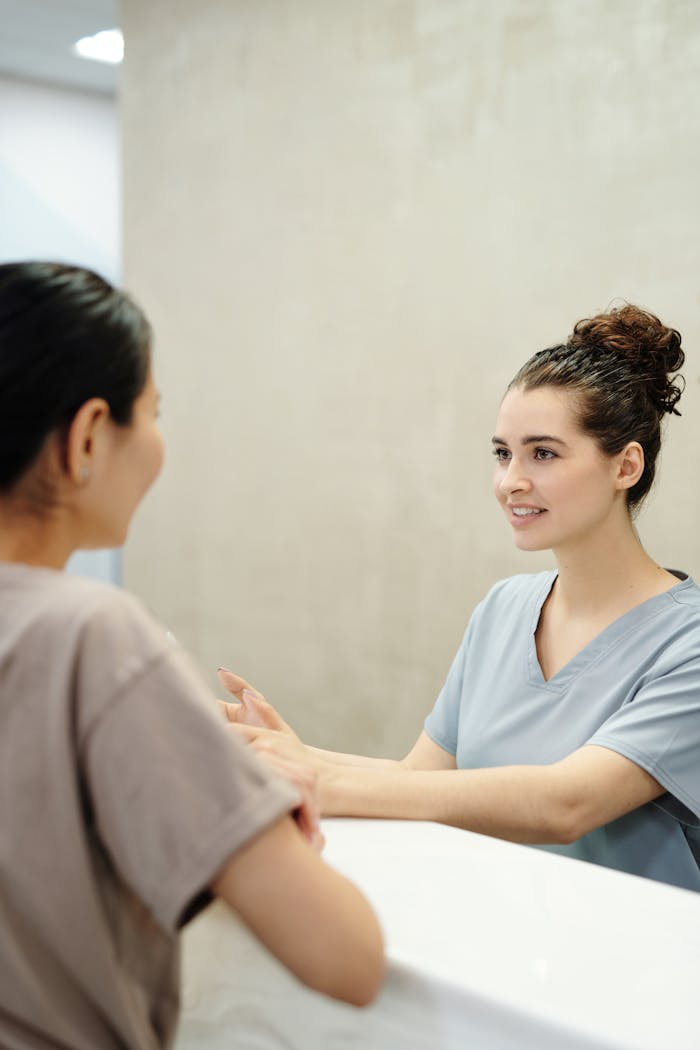 Nurse in conversation with patient at a medical reception desk, emphasizing care and support.
